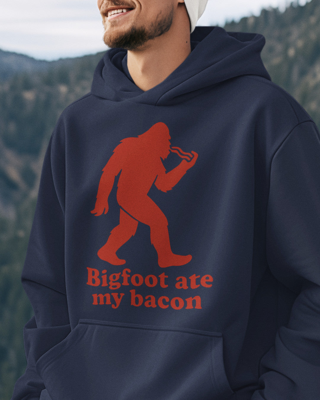 Man wearing a navy Bigfoot Ate My Bacon Hoodie