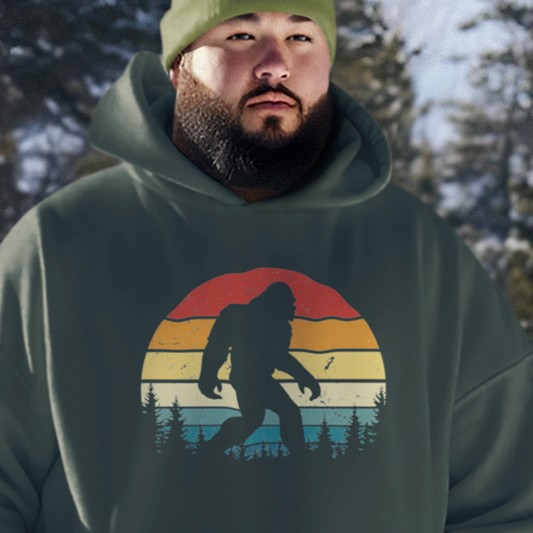 man wearing a forest green retro sunset Bigfoot hoodie